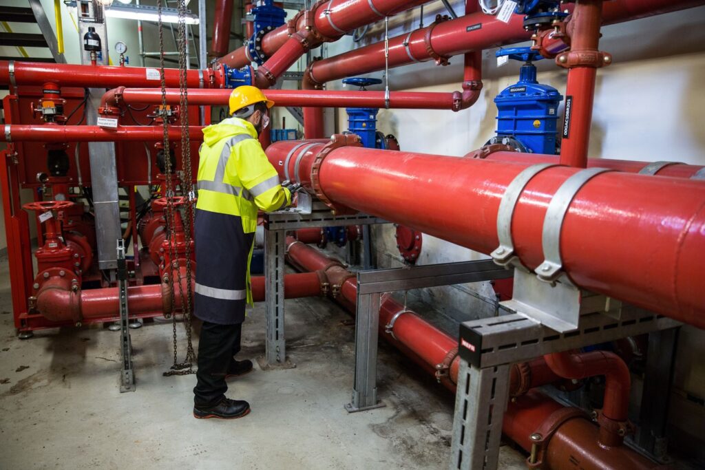 Technician inspecting piping in a commercial mechanical room