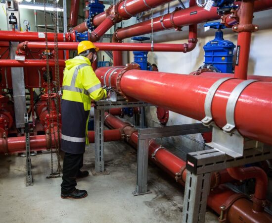 Commercial mechanical room Technician inspecting piping in a commercial mechanical room